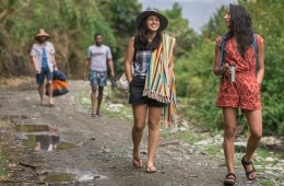 Four friends walk along a dirt path toward a river