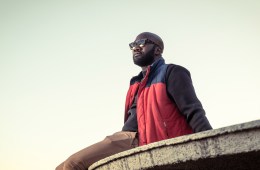 Person wearing sunglasses sitting outside on a ledge