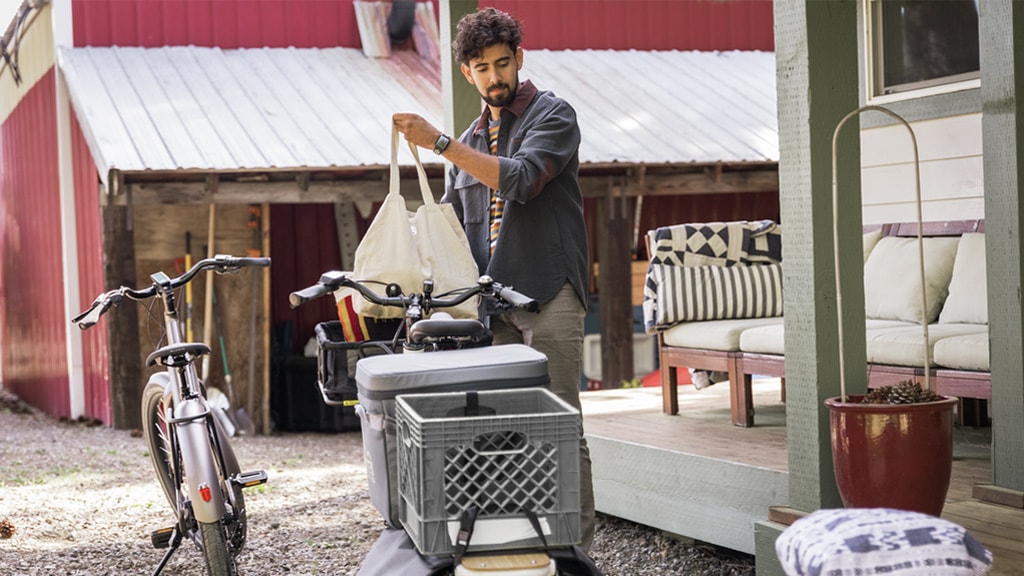 Person loading a bag of groceries onto bike that has a milk crate on the rear rack.