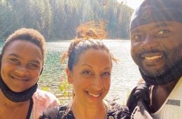 Photo of three people smiling by the river