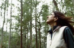 Florence Williams stands in front of trees looking up at the sky.