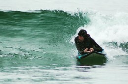 Adaptive athlete, Tim Brown, is on a surfboard catching a wave.