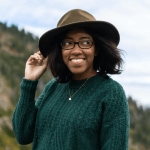 Tori smiling with her hand on the brim of her hat