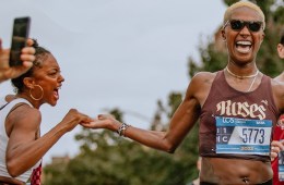 A woman (author Giovanna Fischer) enthusiastically high fives a runner (her teammate Danielle McNeilly) in the middle of a race.