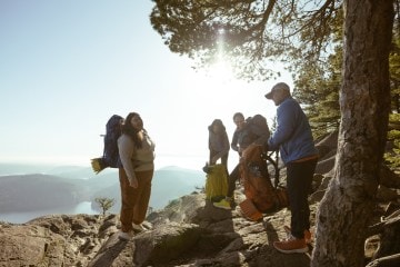 Four people standing on a ridge laughing in the sun