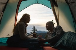 Two people chat inside a tent.