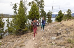 Two people running in cold-weather running gear, including running tights, half-zip sweaters and hydration vests.