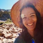 A portrait of the writer Mary Beth Skylis wearing a hat and smiling with her back to the sun