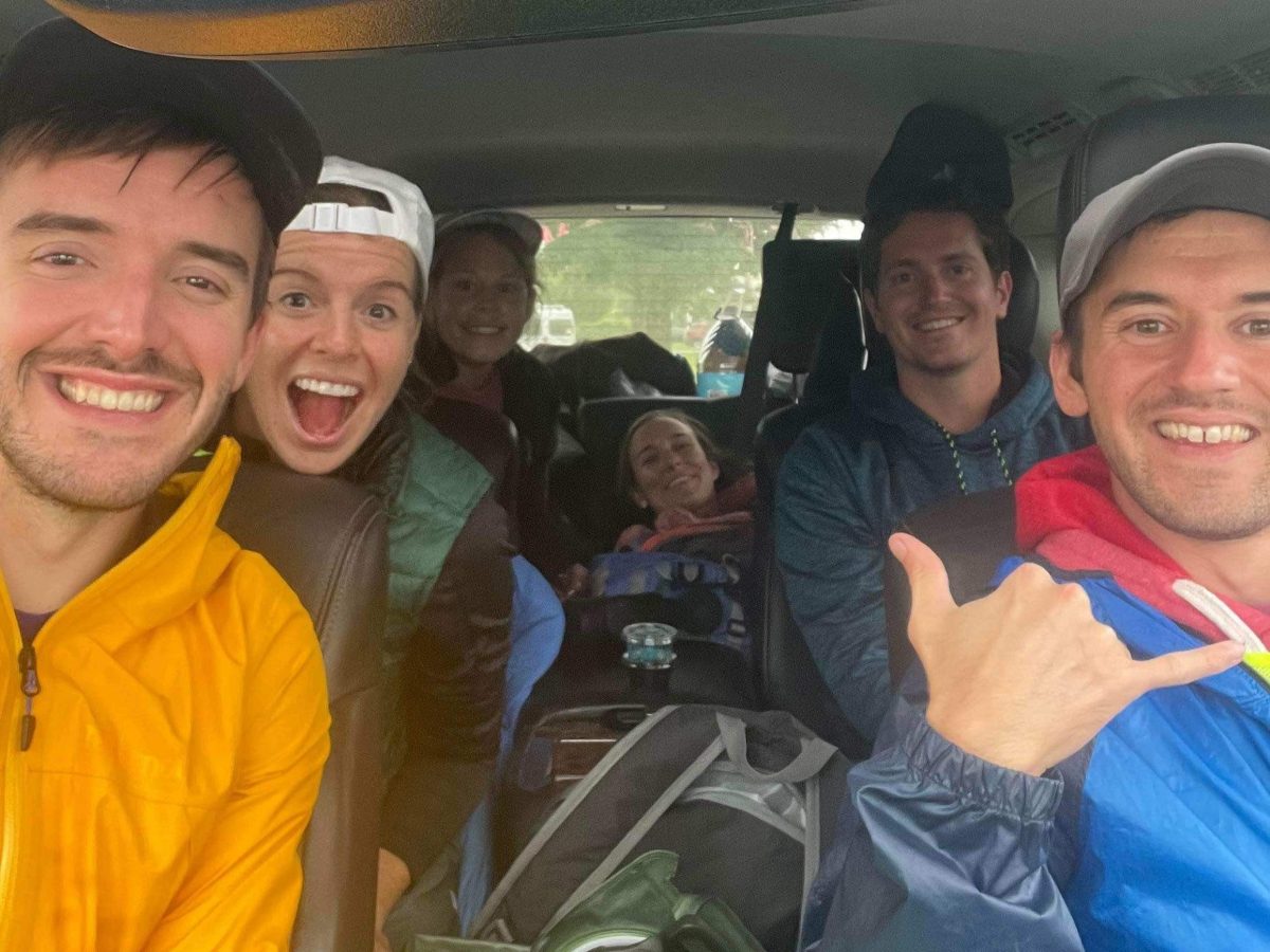 Photo of six smiling people inside a large van