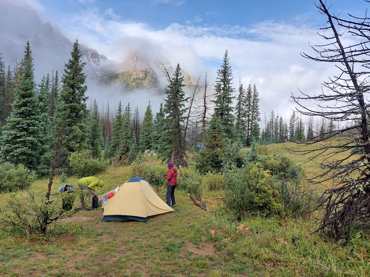 Photo of three campers setting up camp in the wilderness.