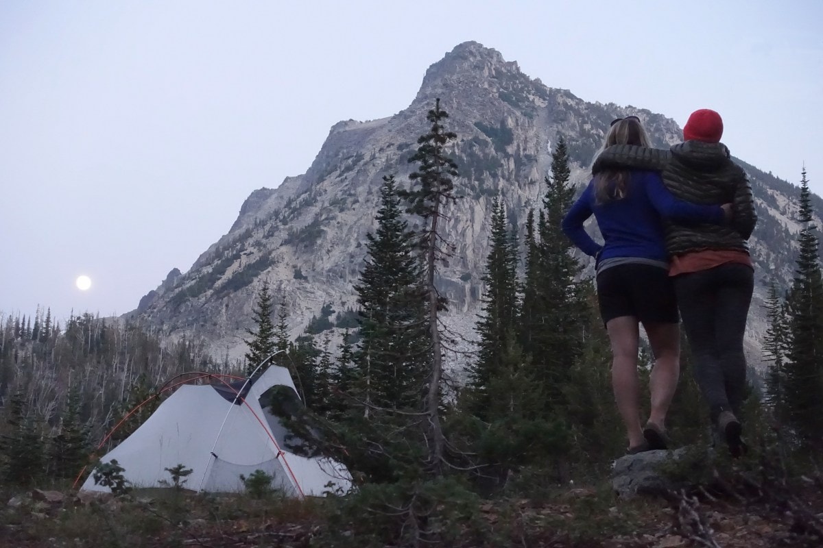 Photo of two people standing in front of their Half Dome Tent, looking at a mountain in the distance.