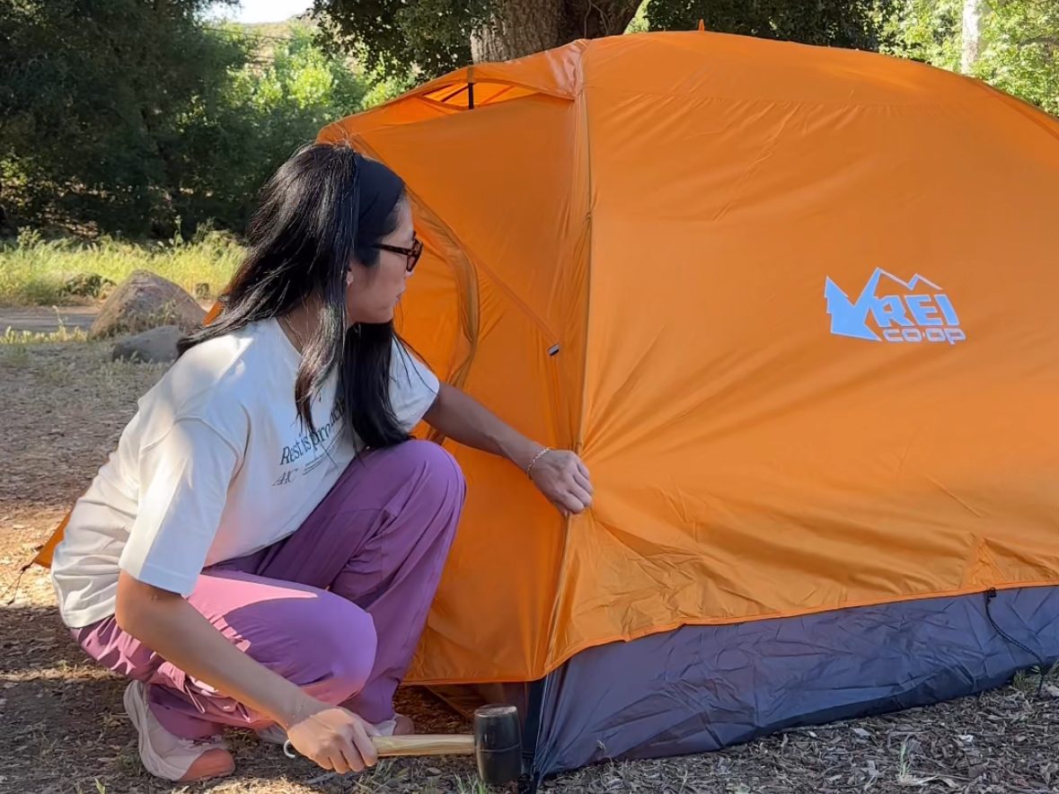 Photo of a woman crouching near her Half Dome Tent.