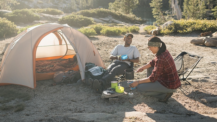 Two backpackers start cooking dinner with a backpacking stove