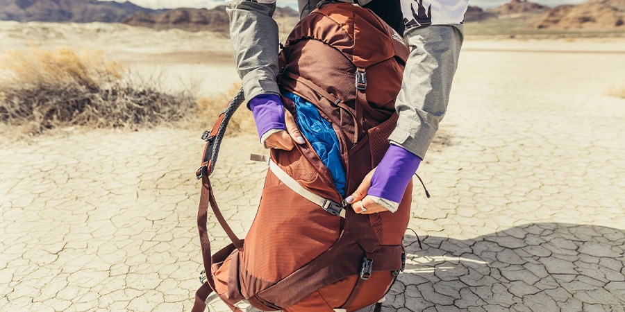 A person closes the zipper on a Gregory Maven backpack