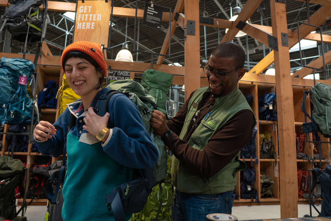 One person helping another fit a backpack