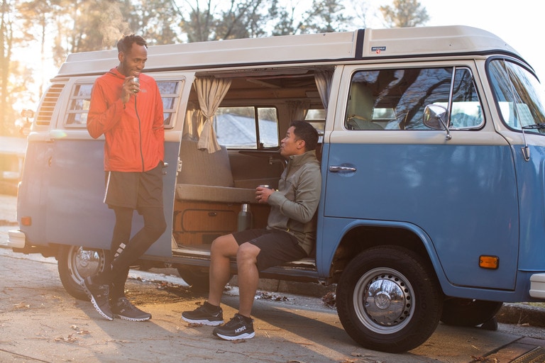 Two people are chatting outside of a camper van.