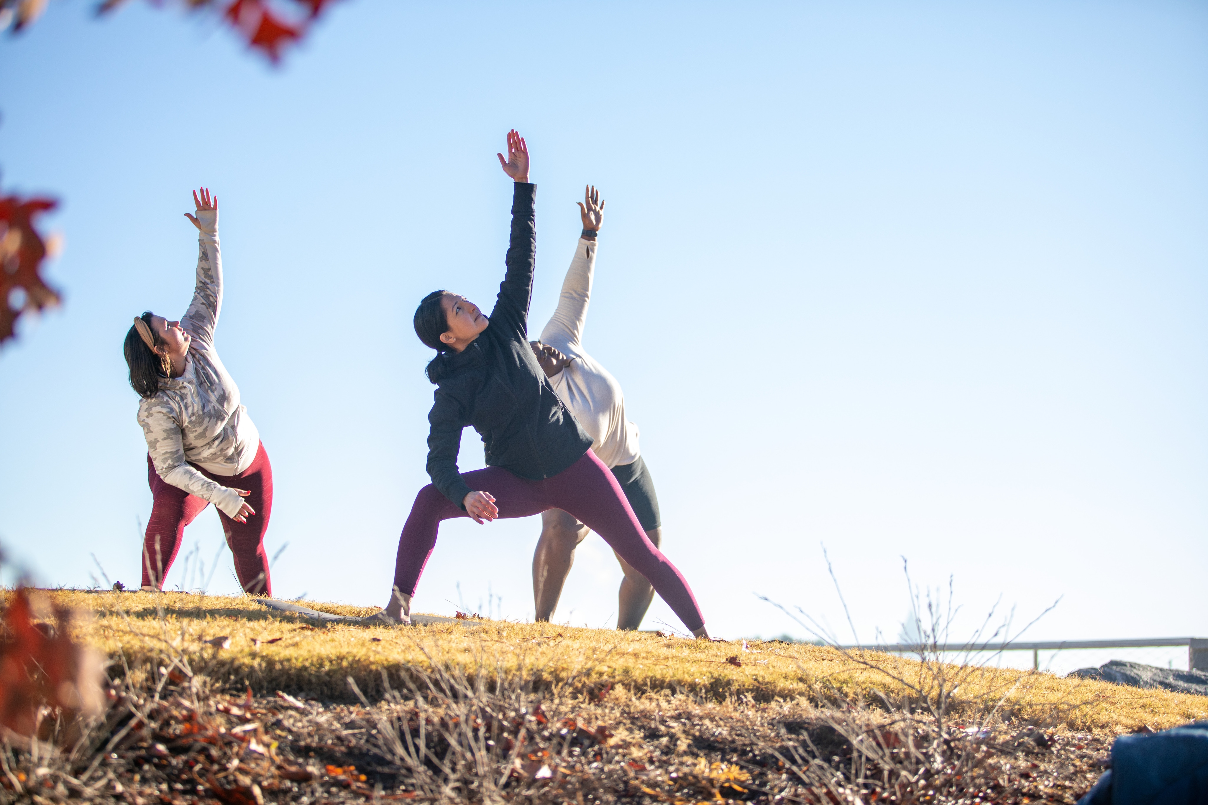 Three women practice yoga in the park