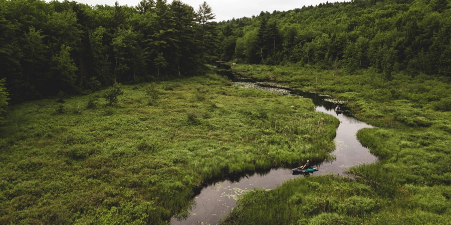 two kayakers fishing along a lazy river, as seen from the above