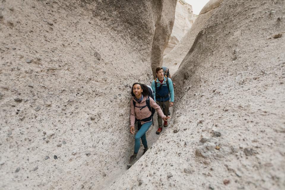 A woman and a man backing through a narrow canyon