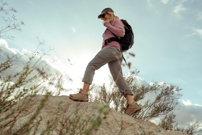 A person hikes over a desert landscape with rolled-up pants