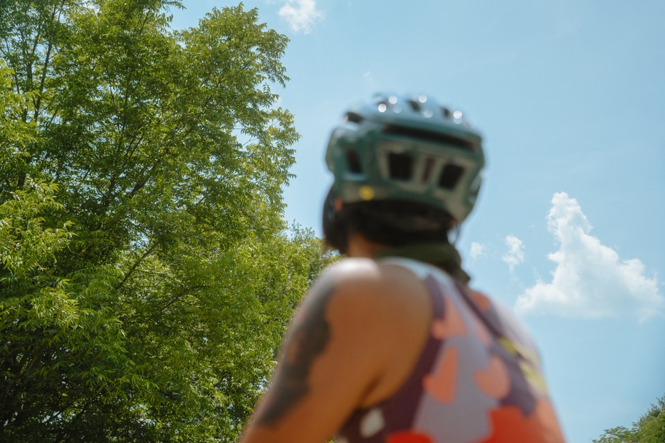 A young person wearing a bike helmet enjoys time outside in nature.