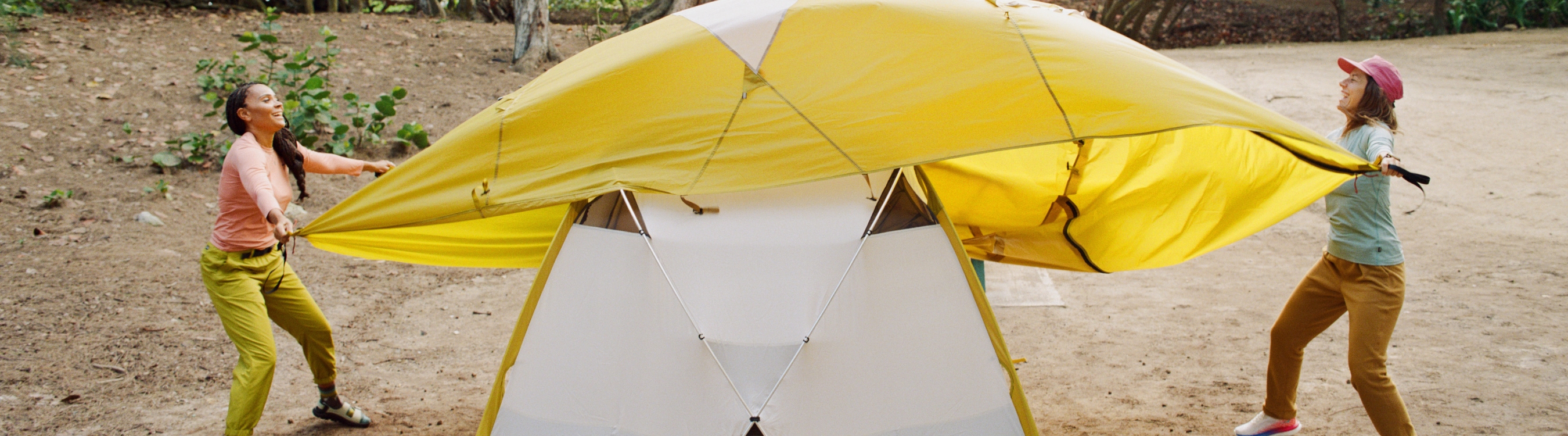 Two campers putting the rain fly over their Basecamp tent.