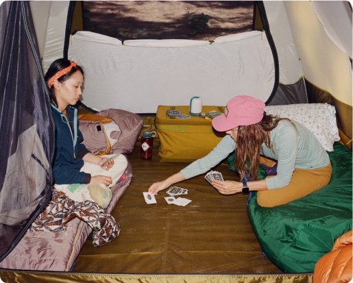 Campers playing cards in their tent.