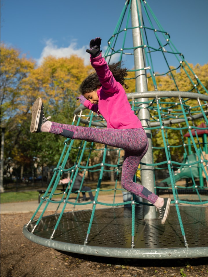 A child jumping in the air at a park playground.