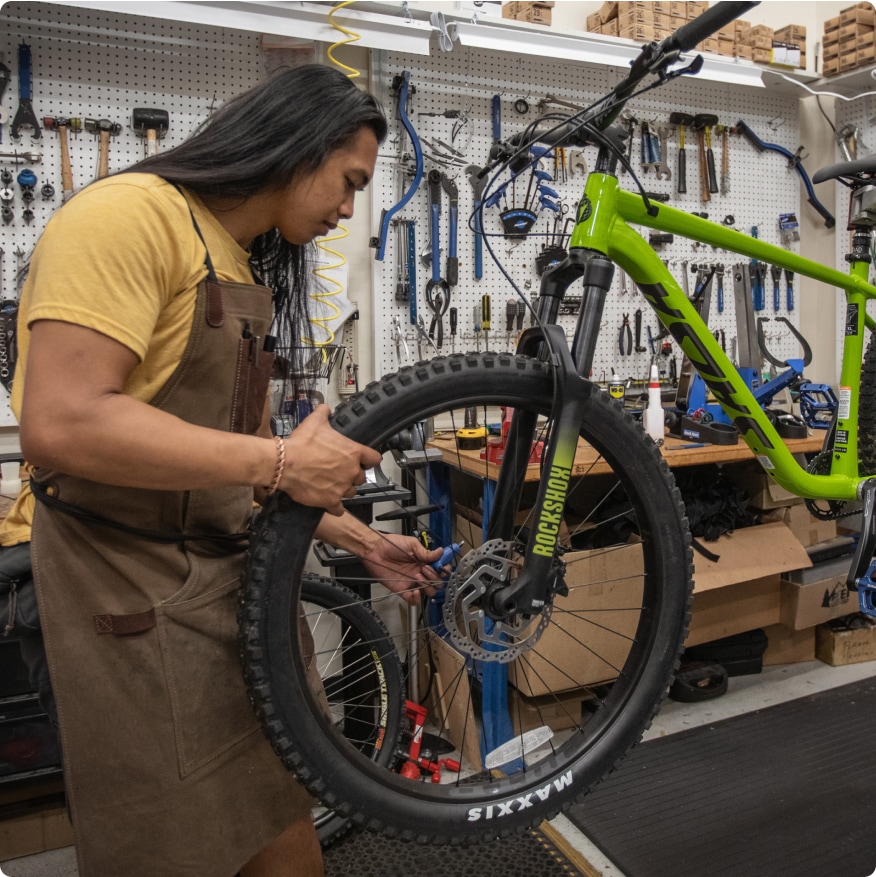 A bike technician adjusts a wheel.