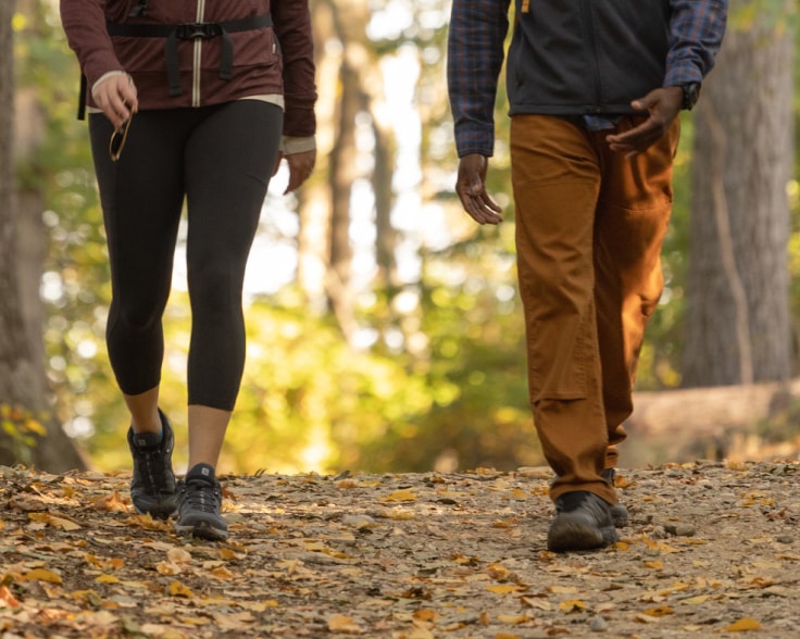 A close shot of two people walking on a trail.