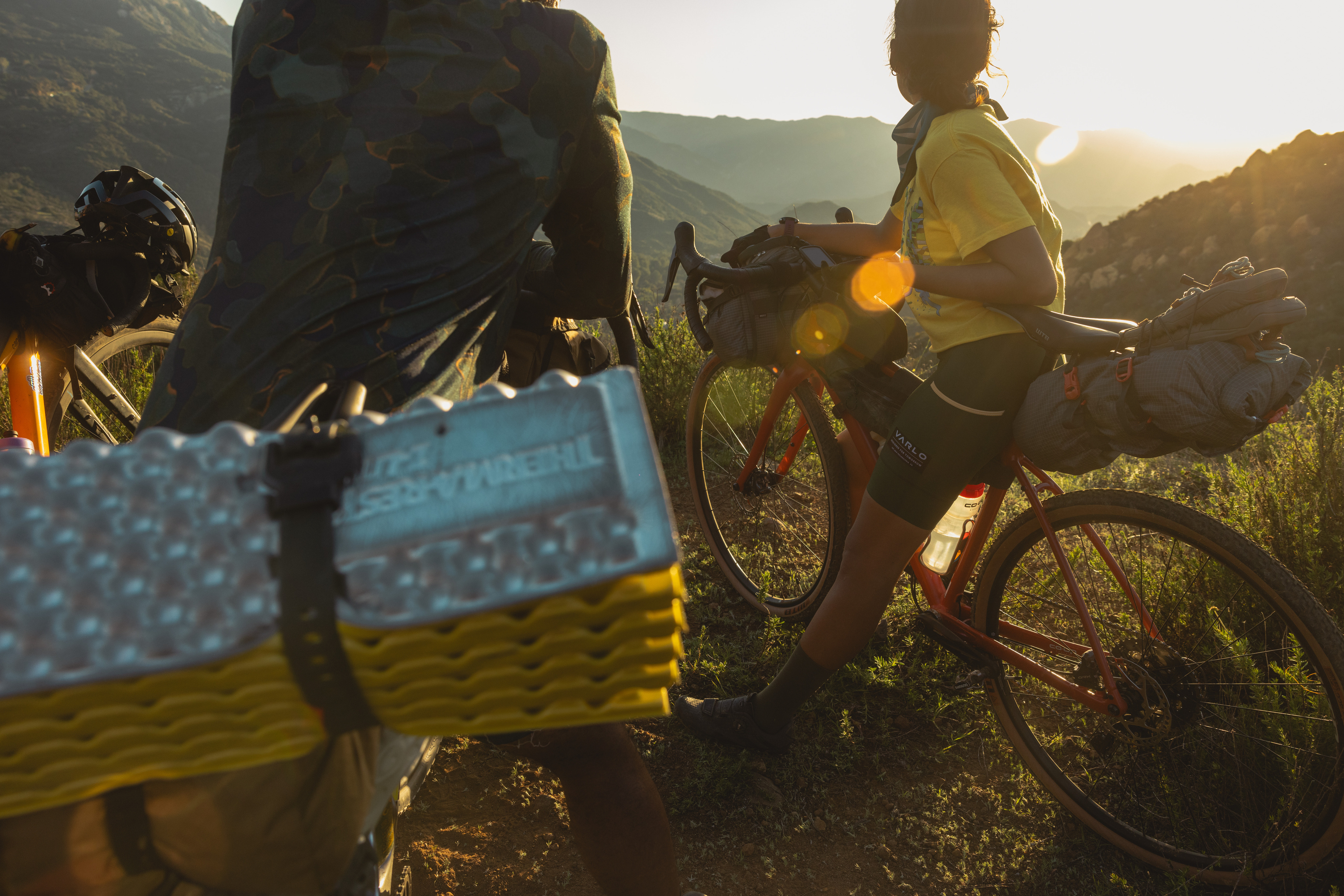 Image of two bike packers on a hill at sunset