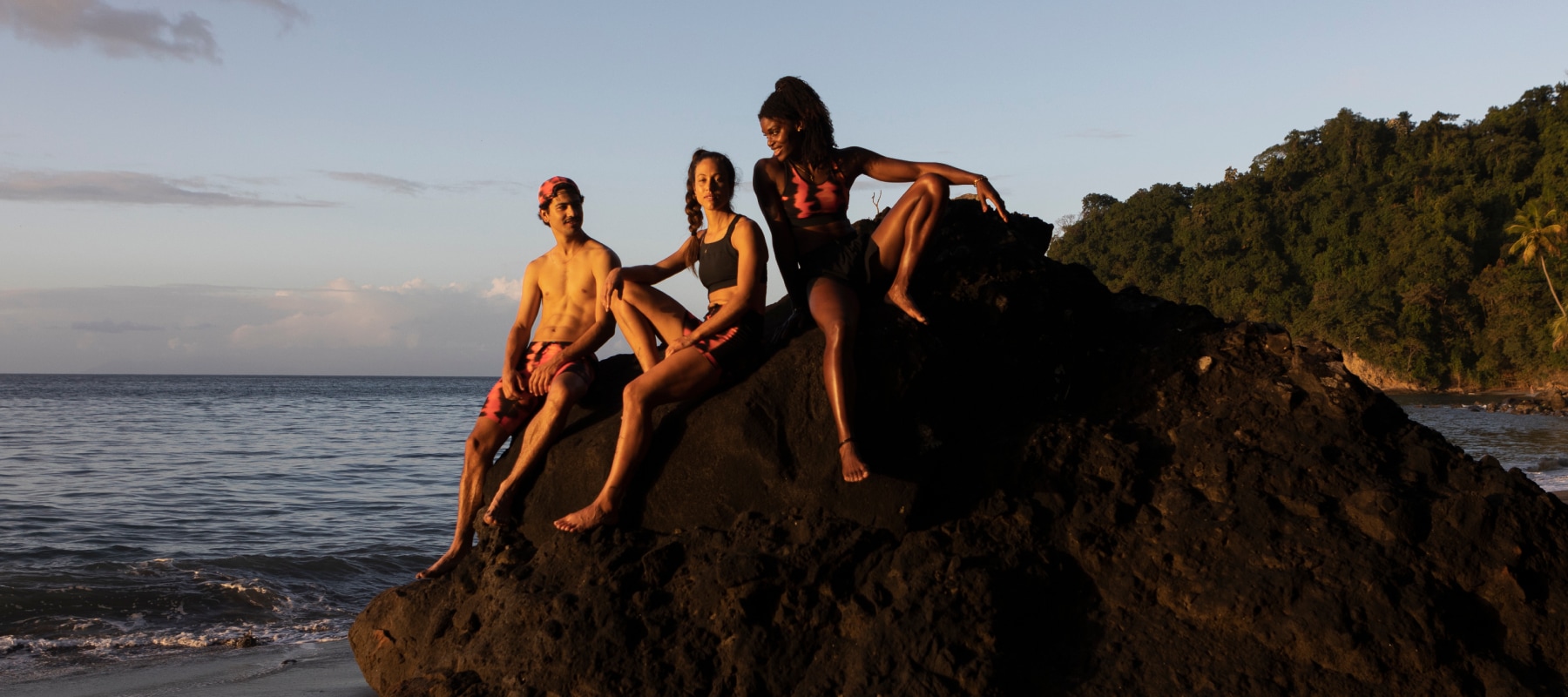 A group of swimmers perch on a rocky island enjoying the last bit of warmth from the setting sun.