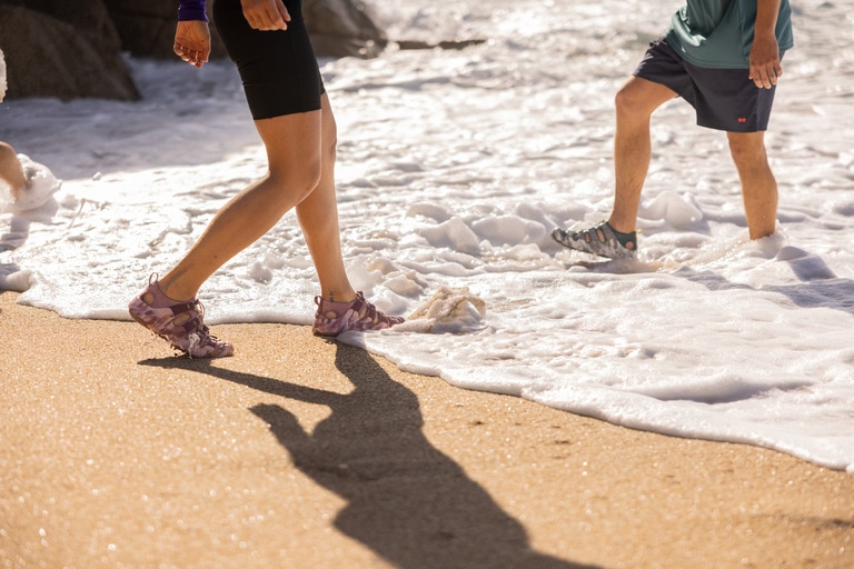 Two people wearing Keen Hyperport H2 Sandals play in the ocean.