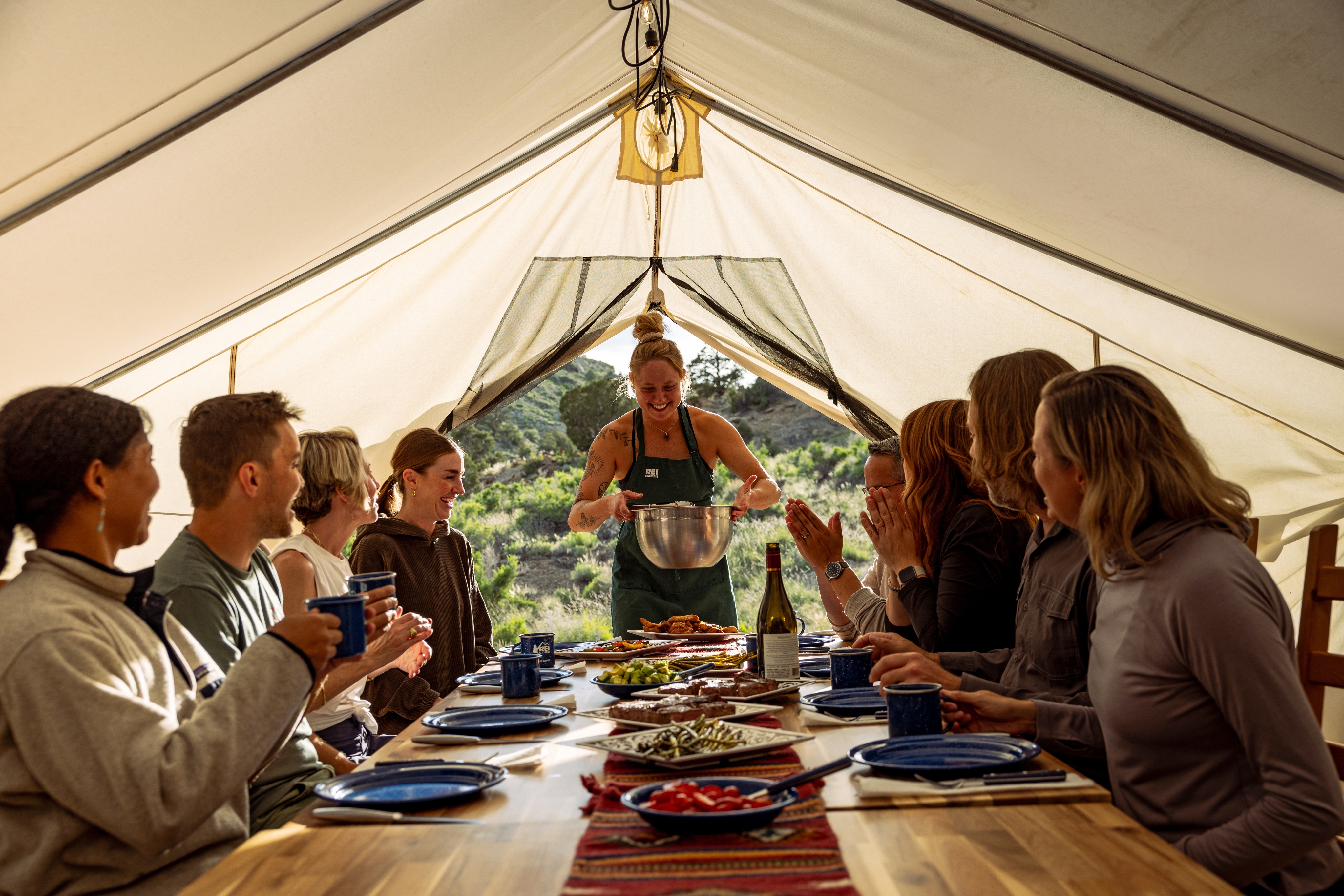 A group of people enjoying dinner underneath a tent.