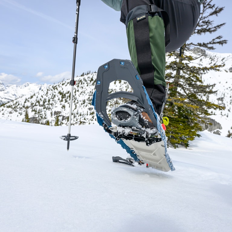 A close up a snowshoe mid-step above the snowy ground