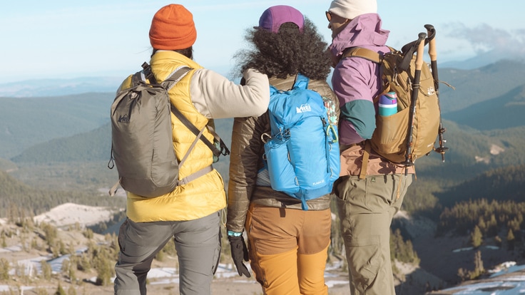 Three people stand at the top of a viewpoint with their backs to the camera