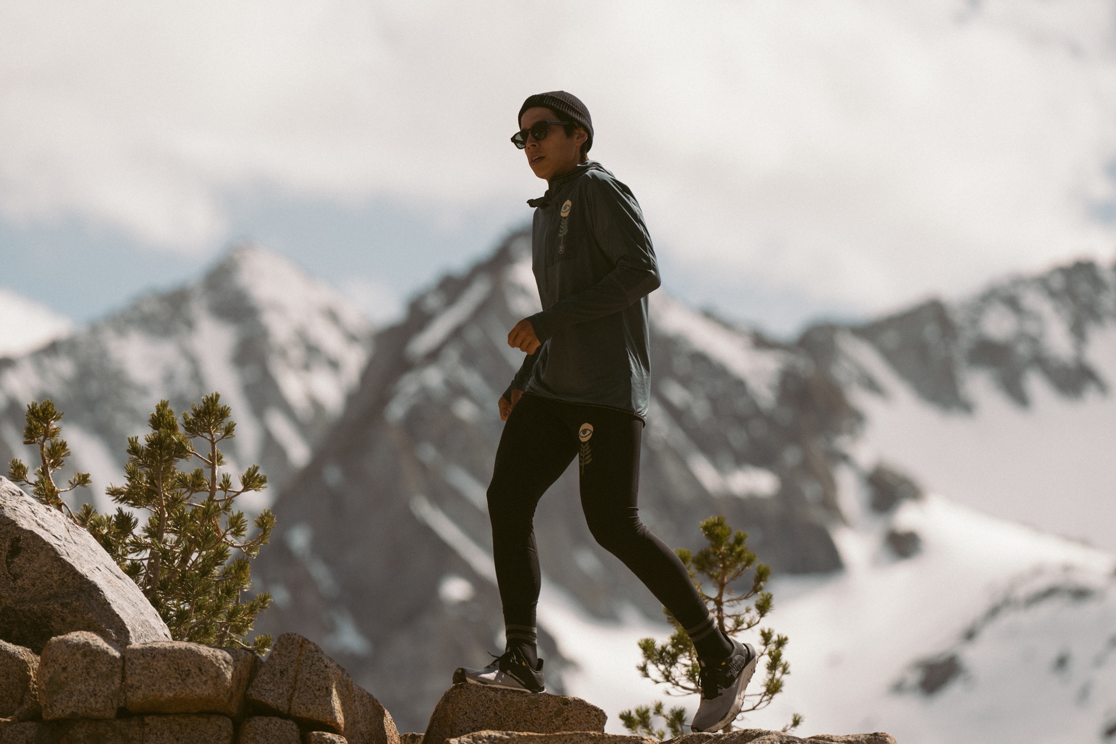 A lone runner on a trail with snowy peaks in the background.