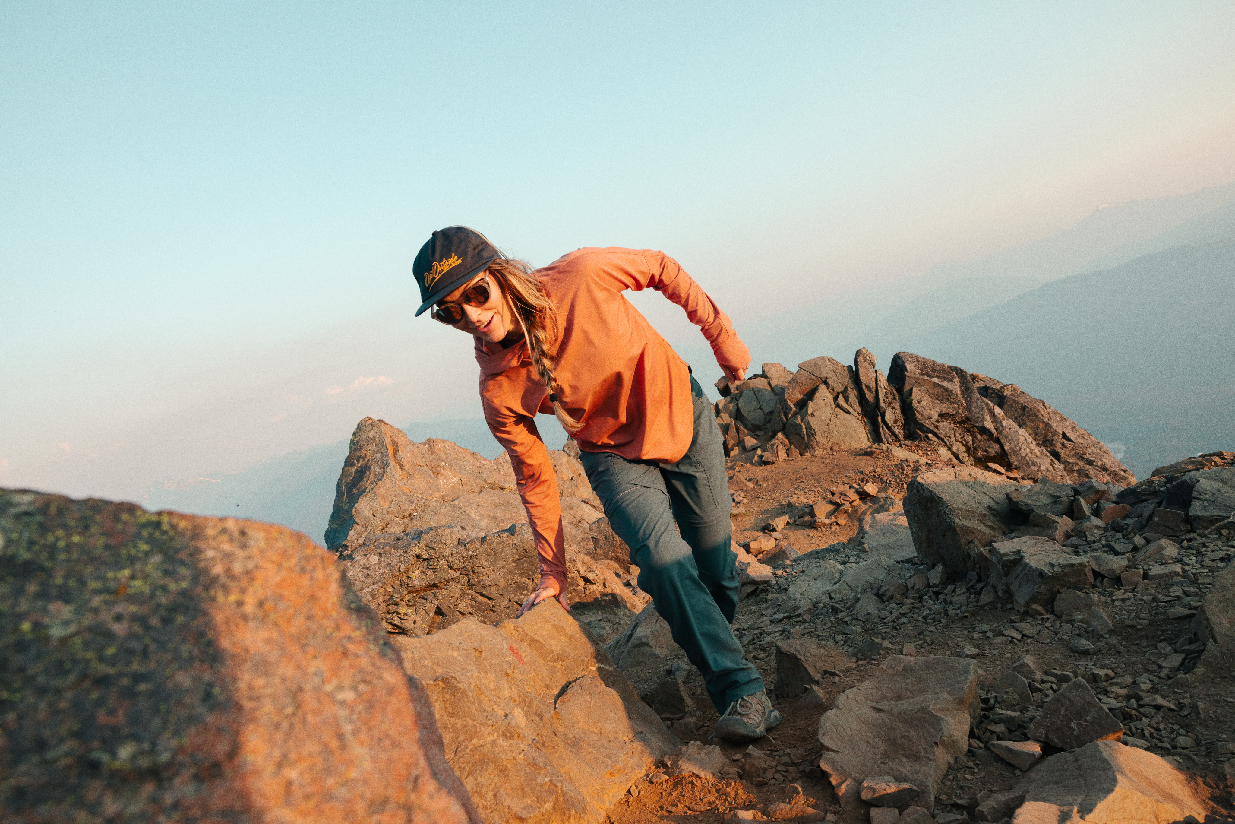 A person wears a sun shirt while hiking along a scenic peak.