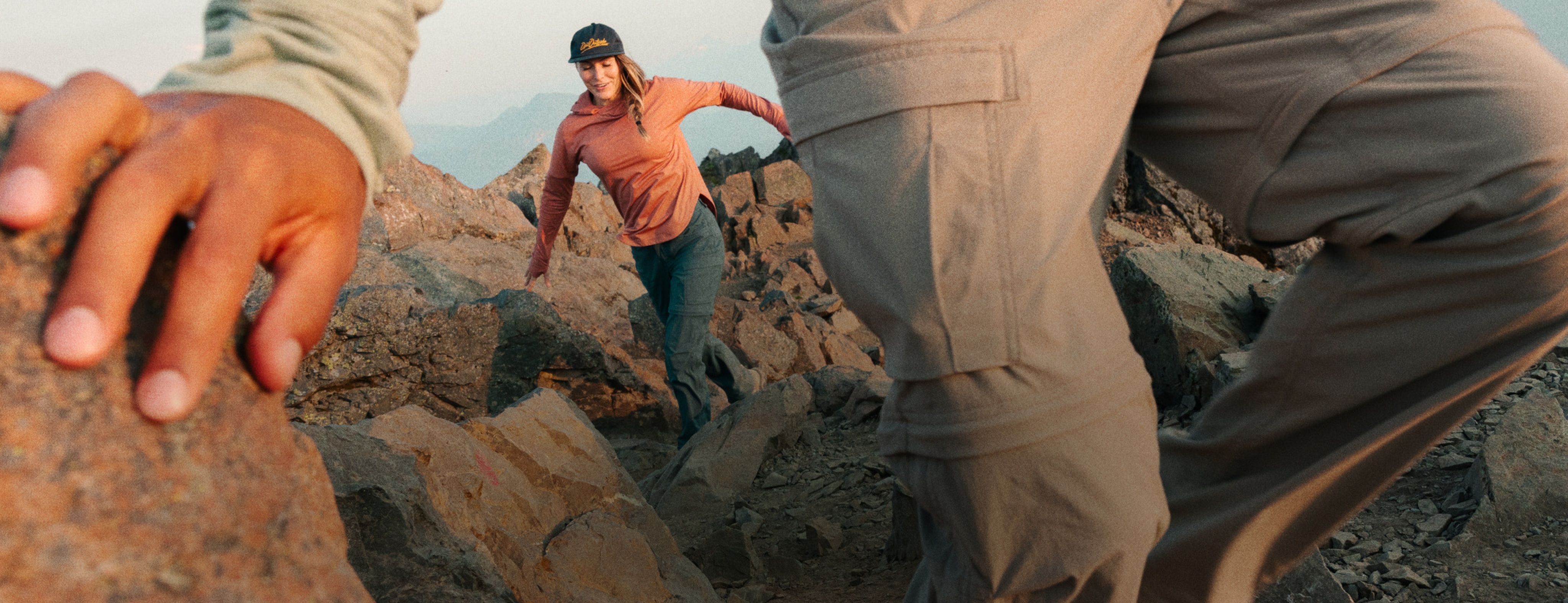 A couple hikers scrambling down a rocky path.