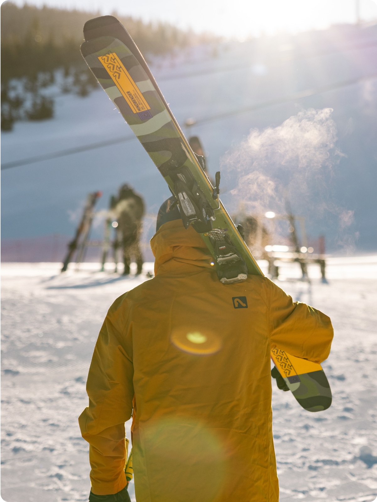 A person holding their skis in front of other skiers.