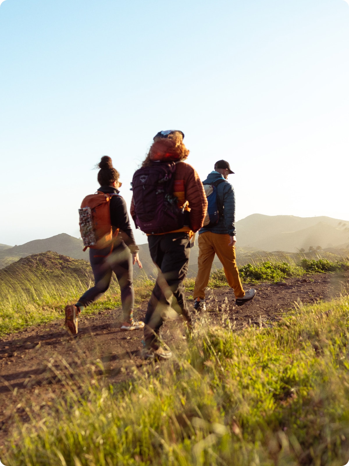 Three people hiking on a mountainous trail. 