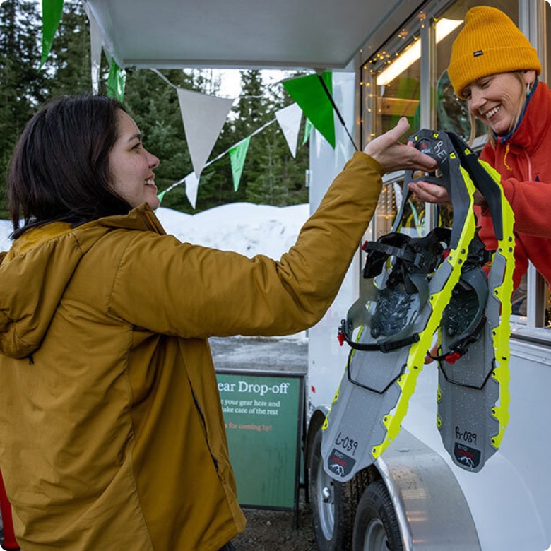 A person renting snow shoes from another.