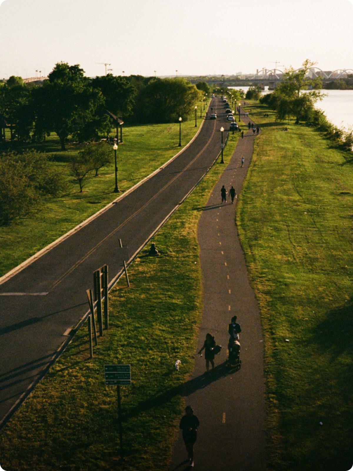 A group of people hiking on a trail by the side of the road.