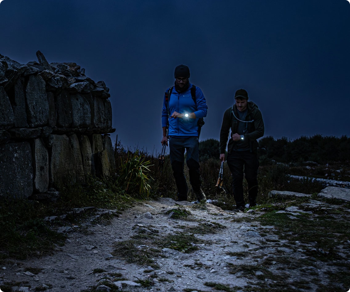 Two people hiking in the dark with their solar charging Garmin sport watches.