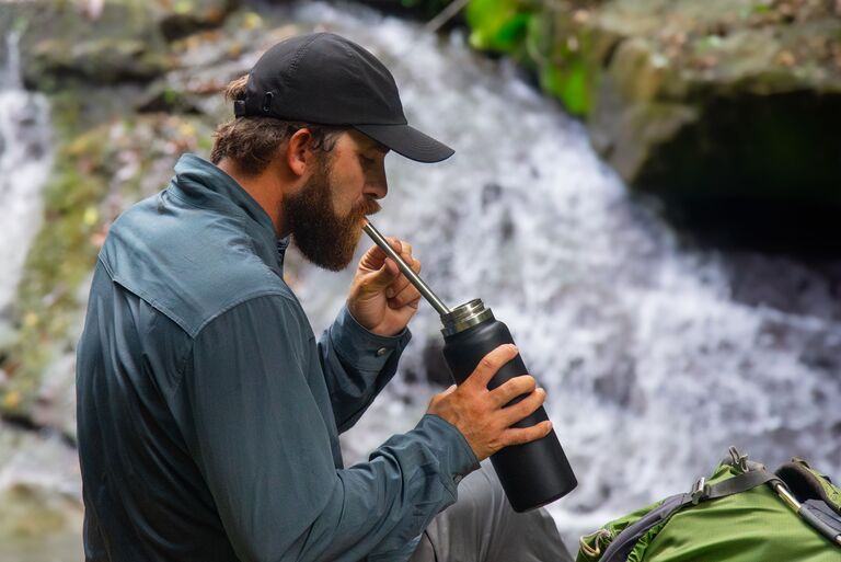 A person sipping through a straw-type water filtration device.