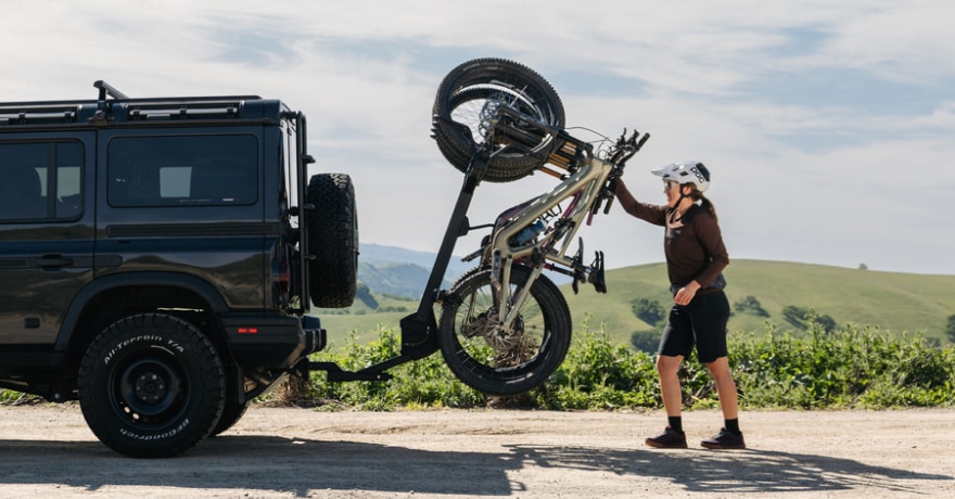 A cyclist loads bikes on an S U V trunk rack.