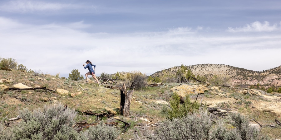 A woman running uphill across a desert landscape