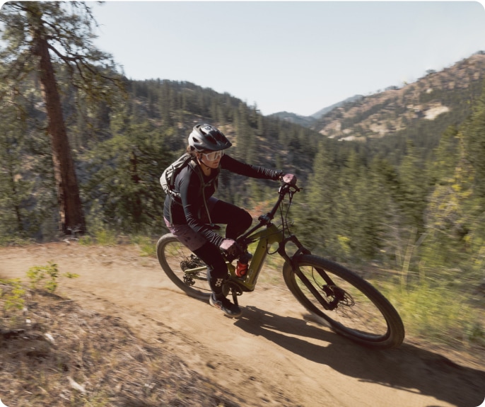 A cyclist rides the Co-op Cycles D R T e 3.1 electric mountain bike.