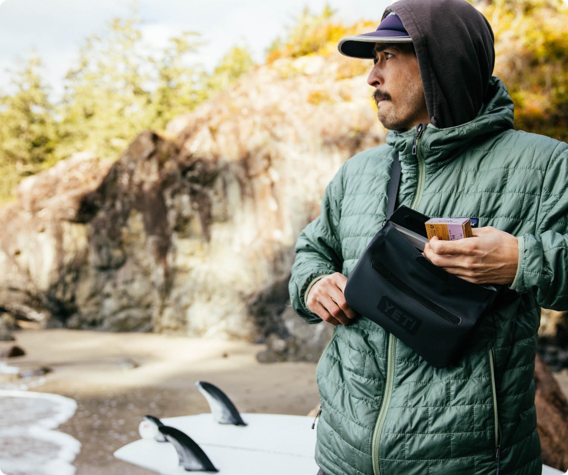 A person wears a YETI Sidekick crossbody bag outdoors.