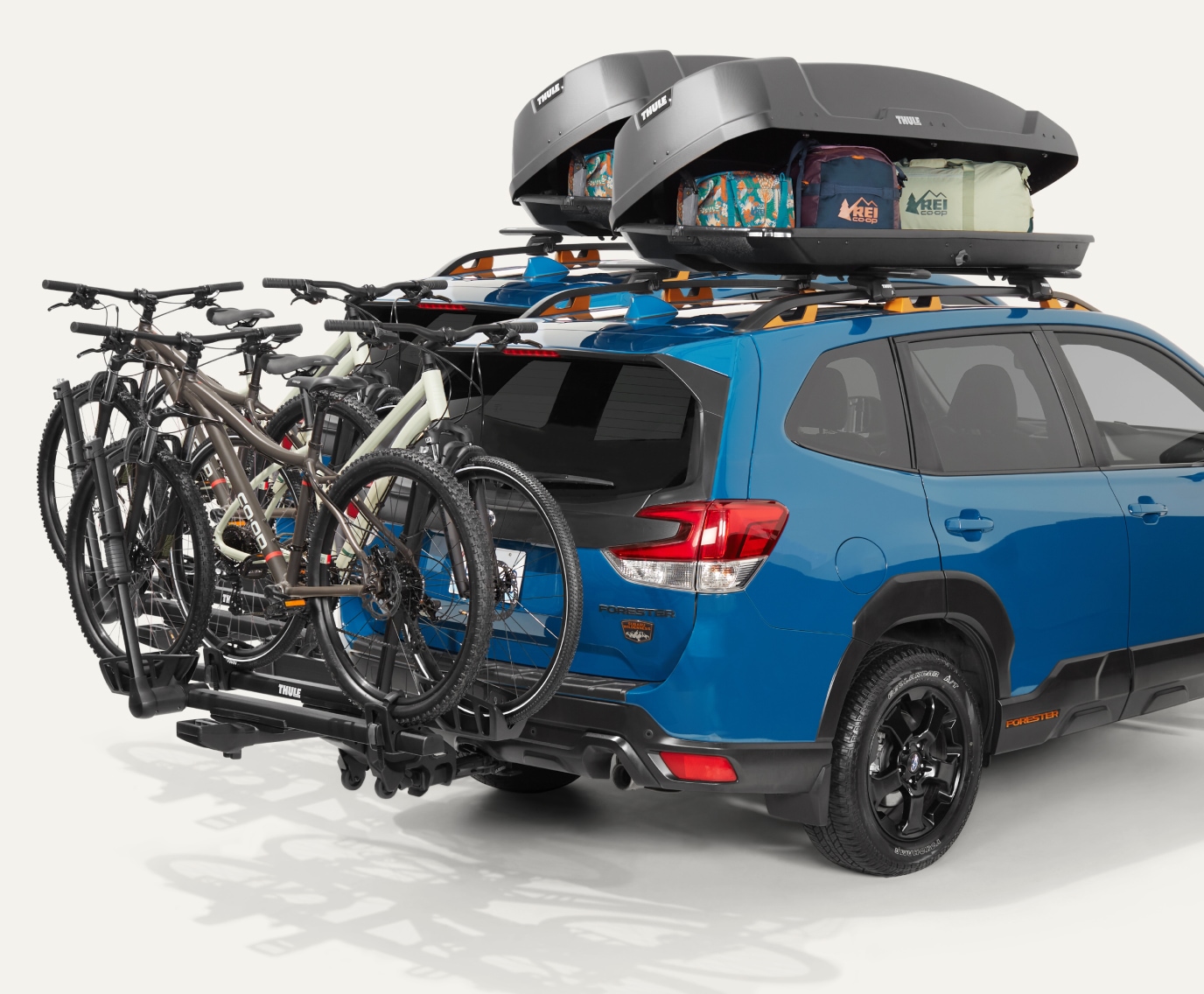 An S U V with a roof box and bike hitch rack.